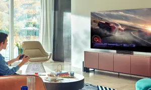 Młody mężczyzna gra w wyścigi na telewizorze 65 cali. Idealna odległość od telewizora 65 cali zapewnia immersję w grze.