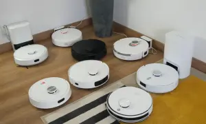 Ranking robotów sprzątających: białe i czarne modele na drewnianej podłodze, gotowe do testów.