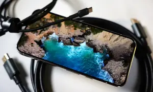 Telefon z widokiem na morze, podłączony kablem USB-C. Obraz z telefonu na TV przez USB-C to łatwy sposób na przeniesienie wrażeń.