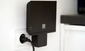 Czarny router Orange funbox 6 podłączony do gniazdka elektrycznego.