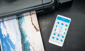 Drukarka drukuje zdjęcie plaży, a na telefonie widać postęp drukowania. Czy to drukarka laserowa czy atramentowa?