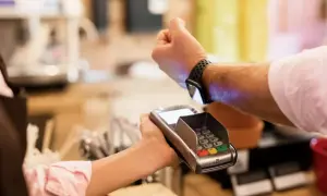 Klient płaci zbliżeniowo zegarkiem z technologią nfc przy terminalu płatniczym.