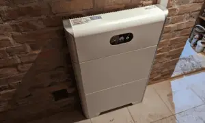 Biały magazyn energii 10kW, stojący przy ceglanej ścianie, zapewnia niezależność energetyczną.