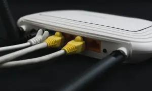 Router z podłączonymi żółtymi i białymi kablami sieciowymi. Ten kabel od internetu zapewnia połączenie.