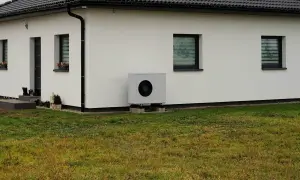 Nowoczesna pompa ciepła przy białym domu. Idealna do ogrzania domu 150m2, zapewnia komfort i oszczędność.