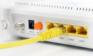 Żółty kabel sieciowy podłączony do portu LAN3 routera. Widoczne też złącze CATV i zasilania.
