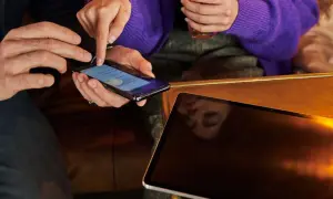 Dwie osoby przyglądają się ekranowi telefonu, być może szukając sposobu, jak powiększyć klawiaturę w telefonie, by wygodniej pisać.