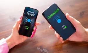Dwie dłonie trzymają telefony. Na jednym ekranie "Personal Hotspot Activated...", na drugim "Connected! Wi-Fi".