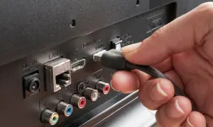 Dłoń podłącza kabel do portu HDMI ARC w telewizorze. Dowiedz się, hdmi arc co to za funkcja.