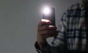 Dłoń trzyma smartfon z włączoną latarką. Dowiedz się, jak wyłączyć latarkę w telefonie, aby oszczędzać baterię.