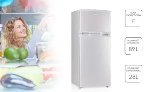 Uśmiechnięta kobieta sięga do otwartej, białej lodówki MPM z warzywami i owocami. Obok lodówki etykiety z klasą energetyczną F i pojemnością.