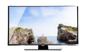 Na ekranie telewizora widok na morze, skały i osobę z rękami w górze. Brak obrazu w telewizorze, gdyby nie ten piękny krajobraz.