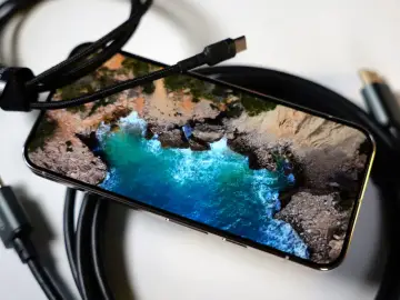 Telefon z widokiem na morze, podłączony kablem USB-C. Obraz z telefonu na TV przez USB-C to łatwy sposób na przeniesienie wrażeń.