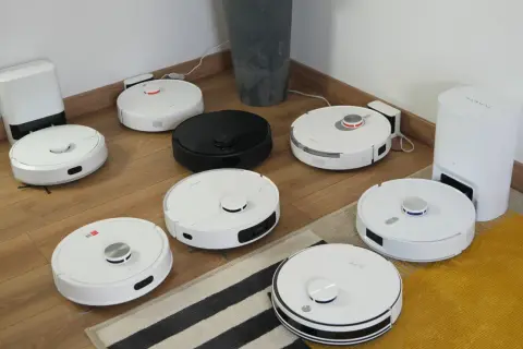 Ranking robotów sprzątających: białe i czarne modele na drewnianej podłodze, gotowe do testów.
