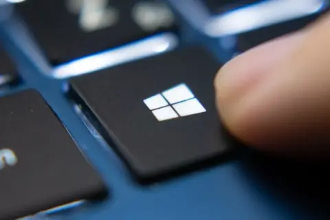 Palec naciska klawisz Windows, rozpoczynając aktualizację sterowników Windows 10.