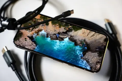 Telefon z widokiem na morze, podłączony kablem USB-C. Obraz z telefonu na TV przez USB-C to łatwy sposób na przeniesienie wrażeń.