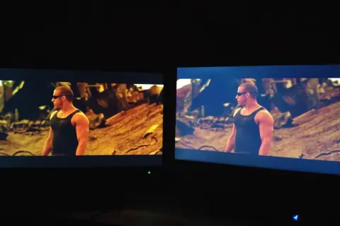 Dwa monitory pokazują tę samą scenę z filmu. Na lewym monitorze, z technologią matryca VA, kolory są cieplejsze, a na prawym chłodniejsze.