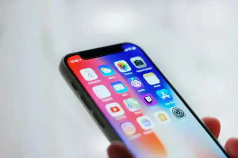 Ekran iPhone'a z ikonami aplikacji. Ustawienia kontroli rodzicielskiej iPhone pomagają zarządzać dostępem do treści.