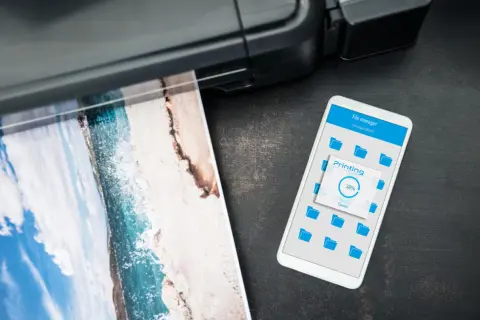 Drukarka drukuje zdjęcie plaży, a na telefonie widać postęp drukowania. Czy to drukarka laserowa czy atramentowa?