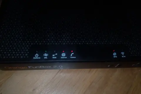 Czarny router Orange FunBox 2.0 z migającymi diodami sygnalizującymi stan połączenia.