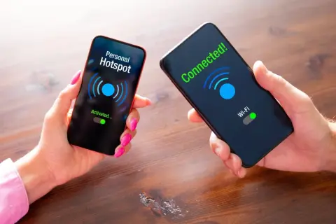 Dwie dłonie trzymają telefony. Na jednym ekranie "Personal Hotspot Activated...", na drugim "Connected! Wi-Fi".