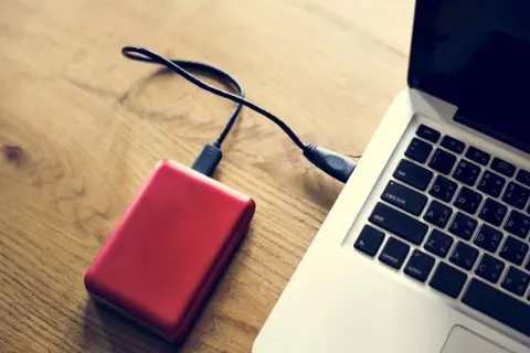 Czerwony dysk zewnętrzny podłączony do laptopa. Komputer nie widzi dysku zewnętrznego, co może być frustrujące.