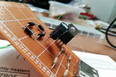 Układ elektroniczny na płytce stykowej z diodami, rezystorami i kondensatorem. Widać też element przypominający warystor.