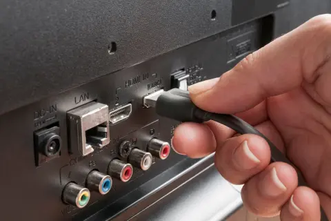 Dłoń podłącza kabel do portu HDMI ARC w telewizorze. Dowiedz się, hdmi arc co to za funkcja.
