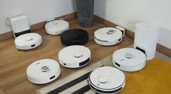 Ranking robotów sprzątających: białe i czarne modele na drewnianej podłodze, gotowe do testów.