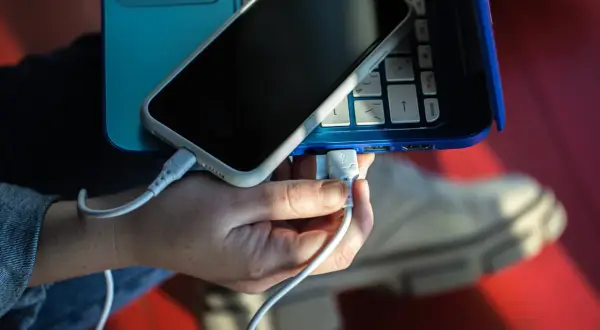 Ręka podłącza telefon do laptopa przez USB. Prosty sposób, jak połączyć telefon z komputerem przez USB, by przesyłać dane lub ładować urządzenie.