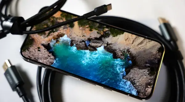 Telefon z widokiem na morze, podłączony kablem USB-C. Obraz z telefonu na TV przez USB-C to łatwy sposób na przeniesienie wrażeń.