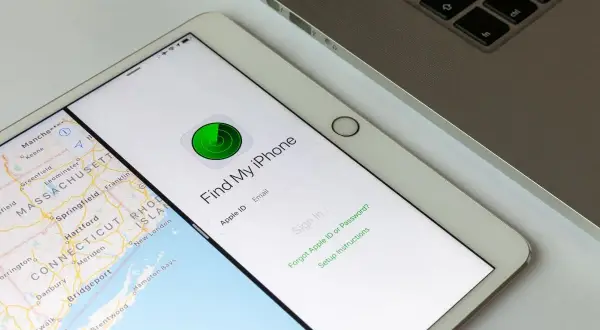 Tablet z mapą i aplikacją "Find My iPhone" do lokalizacji telefonu. Obok klawiatura laptopa.
