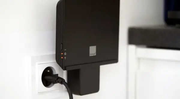 Czarny router Orange funbox 6 podłączony do gniazdka elektrycznego.