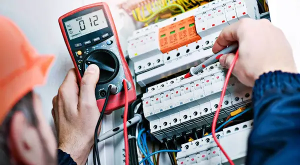 Elektryk z uprawnieniami SEP do 1kV sprawdza instalację elektryczną multimetrem.
