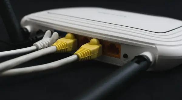 Router z podłączonymi żółtymi i białymi kablami sieciowymi. Ten kabel od internetu zapewnia połączenie.