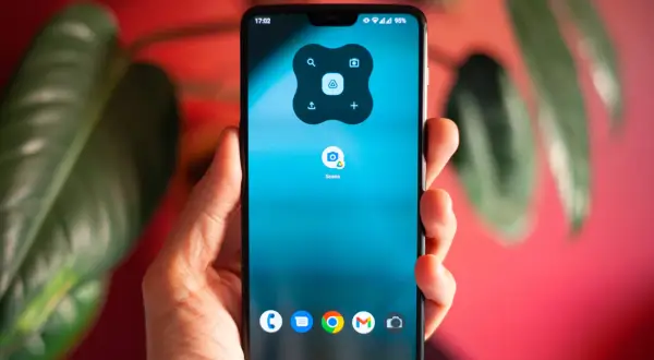 Dłoń trzyma smartfon z ikoną "Scans" na ekranie. To Twój podręczny skaner w telefonie, gotowy do działania.