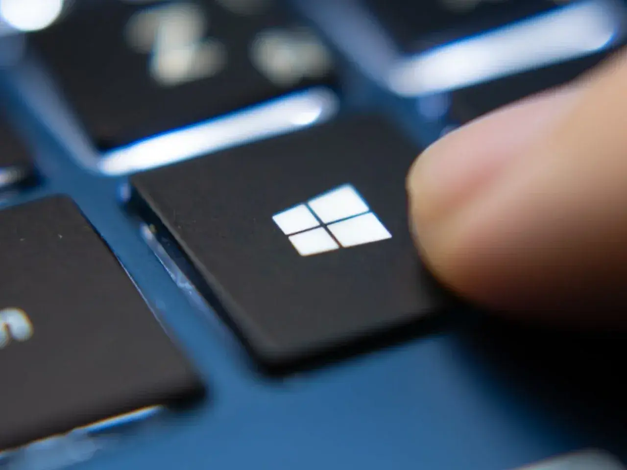 Palec naciska klawisz Windows, rozpoczynając aktualizację sterowników Windows 10.