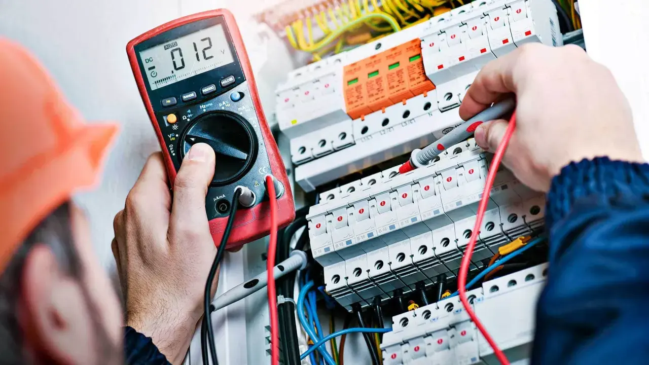 Elektryk z uprawnieniami SEP do 1kV sprawdza instalację elektryczną multimetrem.