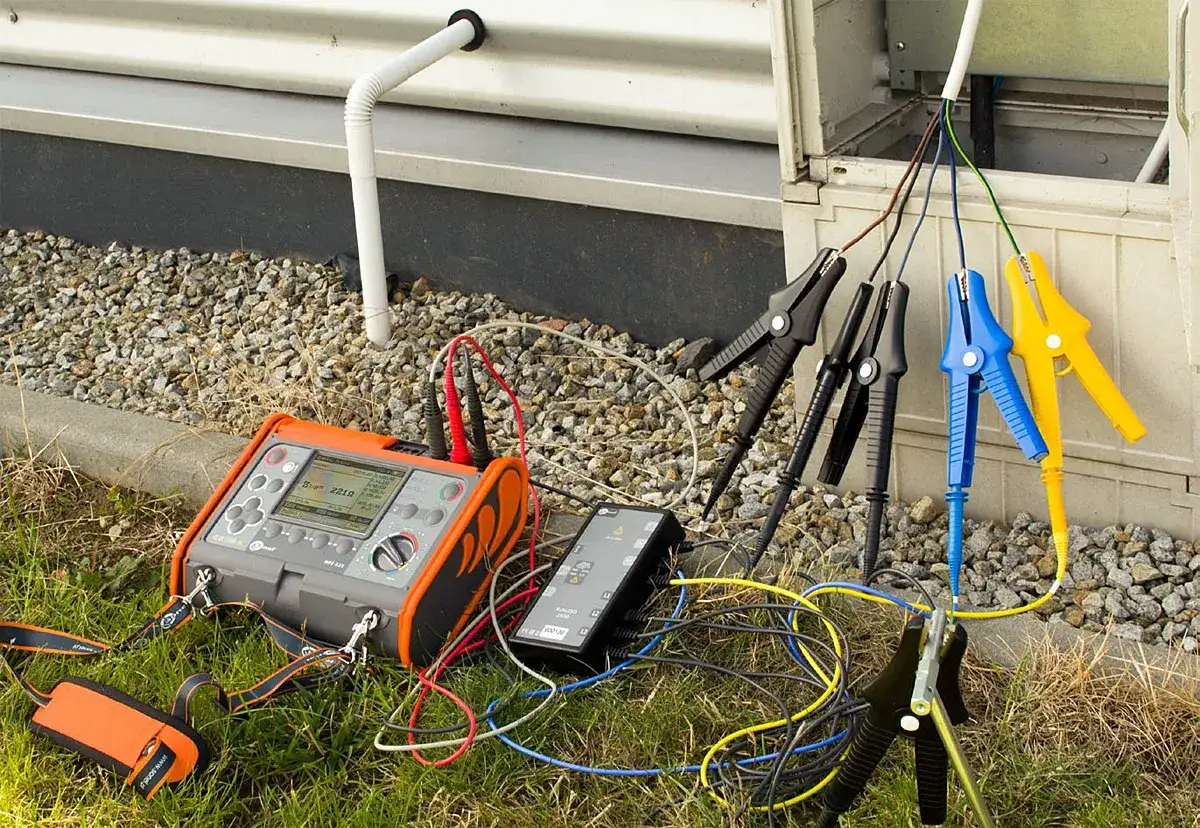 Miernik do badania rezystancji izolacji podłączony do przewodów instalacji elektrycznej. Wynik pomiaru 221Ω.