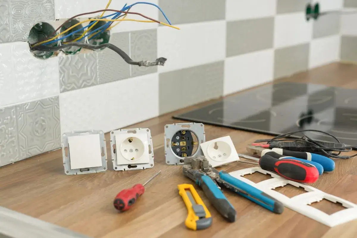 Narzędzia elektryczne i gniazdka czekają na montaż. W tle widać przewody wystające ze ściany, gotowe do podłączenia. To etap prac związanych z wlz.