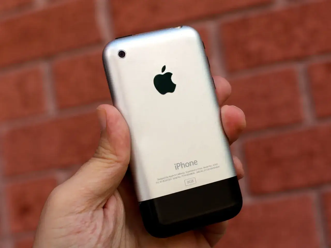 Pierwszy iPhone w dłoni, z widocznym jabłkiem Apple i napisem 