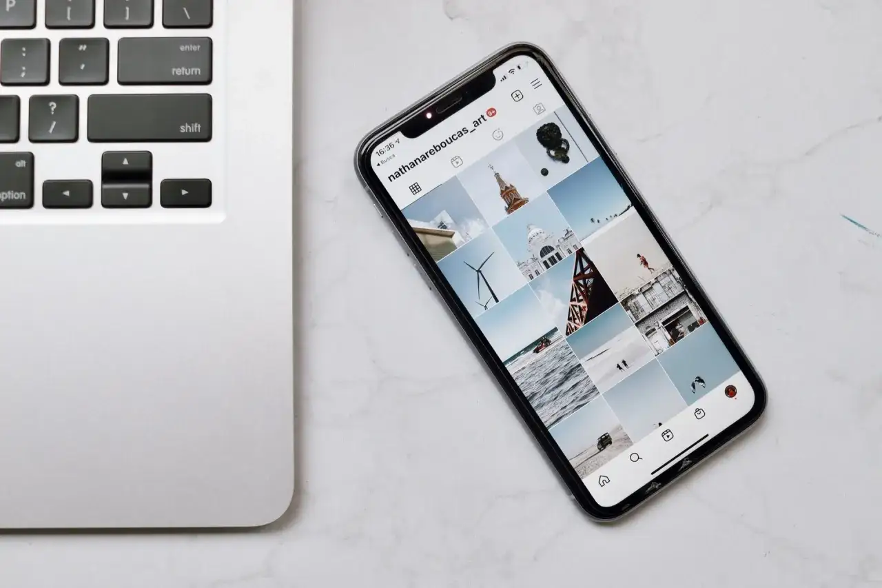 Jak połączyć telefon z laptopem? Na zdjęciu widać smartfon z Instagramem obok klawiatury laptopa.