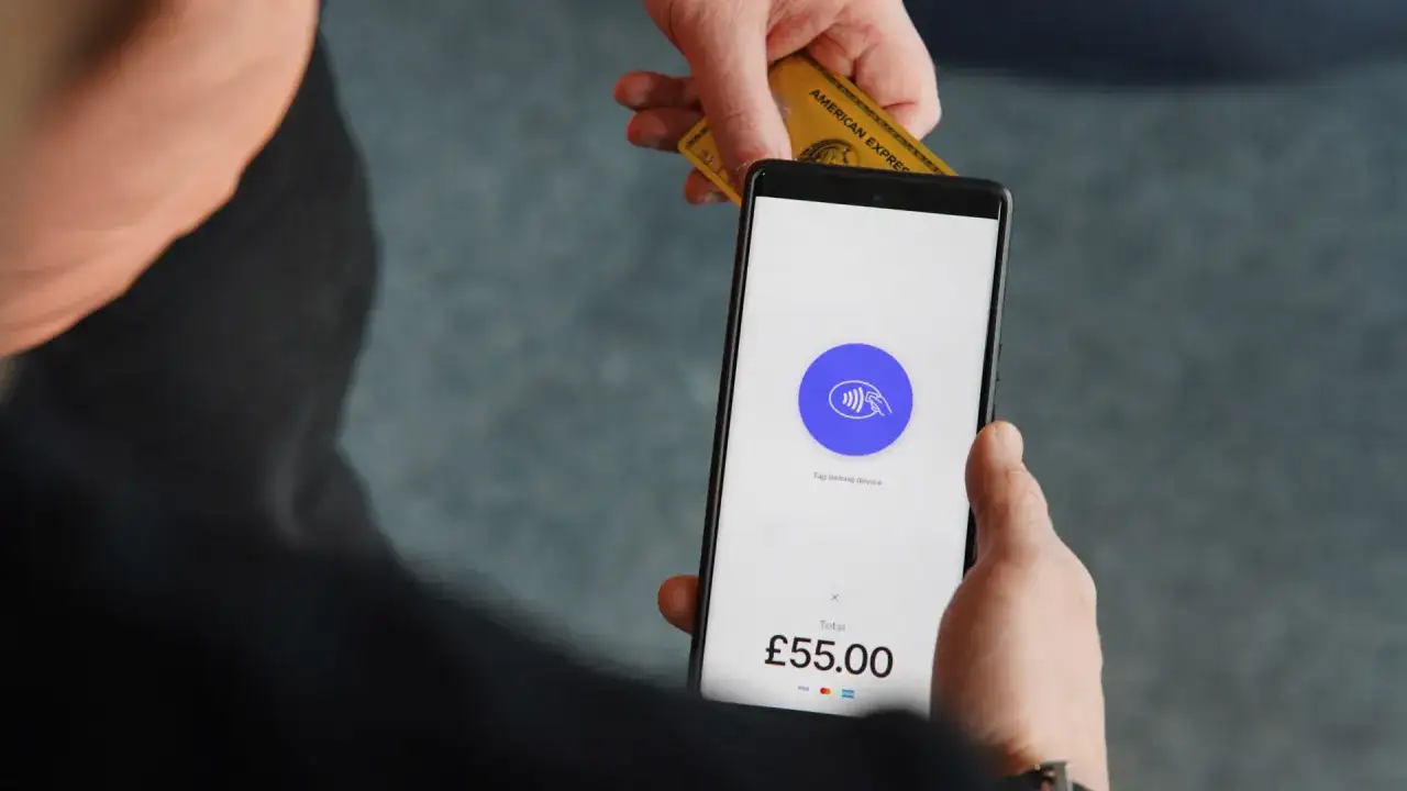 Zbliżenie na telefon z ekranem płatności zbliżeniowych i kartę American Express. Dowiedz się, jak włączyć NFC w telefonie, by płacić bezdotykowo.