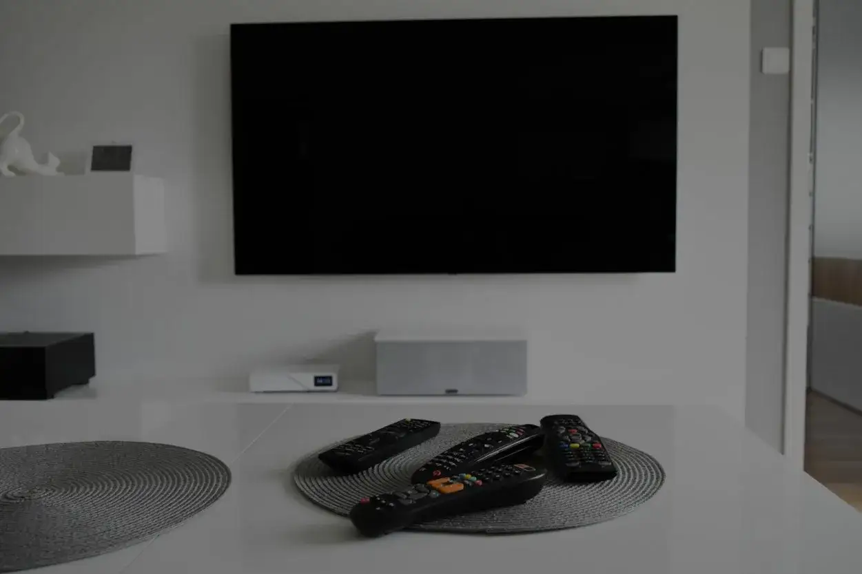 Na stole leżą piloty, a telewizor jest wyłączony. Brak obrazu w telewizorze, czas na relaks.