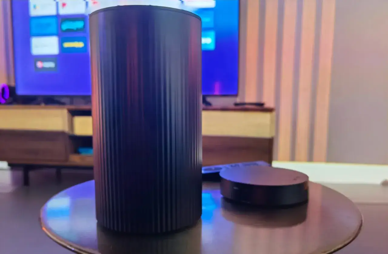 Czarny router i mały dysk na stoliku. W tle telewizor z ikonami aplikacji. Czy to sprzęt do szybkiego internetu? play światłowód opinie.