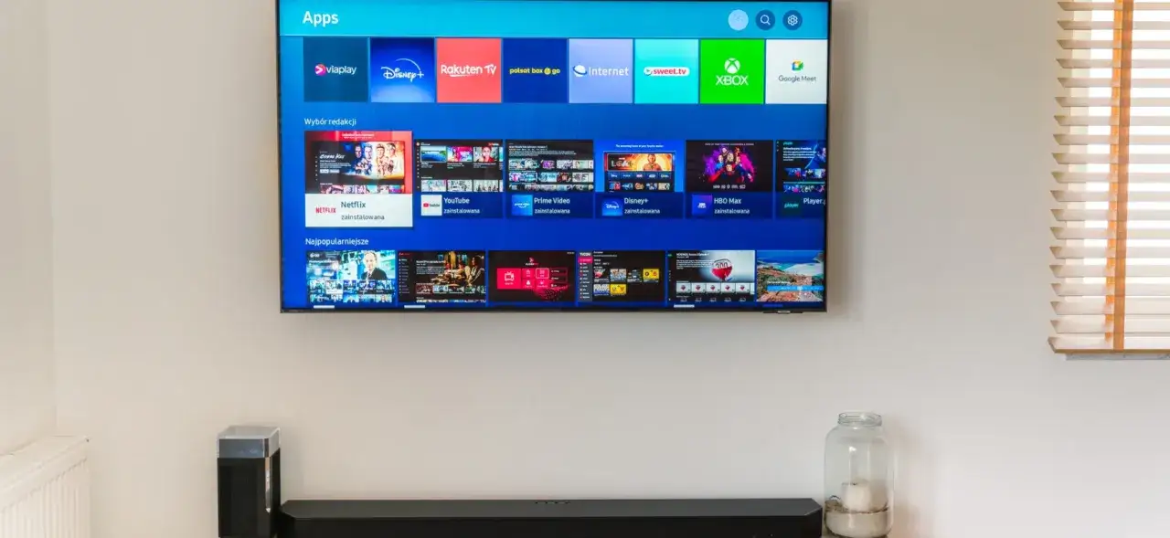 Telewizor z matrycą VA wyświetla ekran aplikacji z ikonami serwisów streamingowych, takich jak Netflix, Disney+, YouTube i HBO Max.
