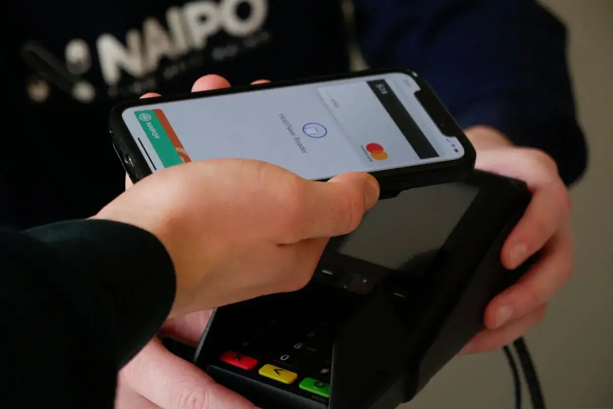 Zbliżenie telefonu z aktywnym płaceniem zbliżeniowym NFC do terminala płatniczego.