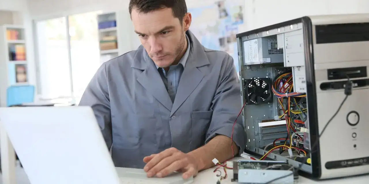 Technik wykonuje diagnozę laptopa, analizując wnętrze otwartej obudowy komputera stacjonarnego.