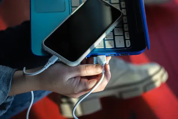 Ręka podłącza telefon do laptopa przez USB. Prosty sposób, jak połączyć telefon z komputerem przez USB, by przesyłać dane lub ładować urządzenie.