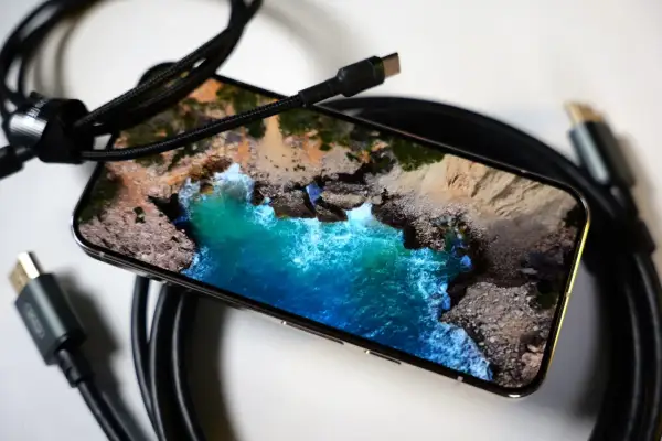 Telefon z widokiem na morze, podłączony kablem USB-C. Obraz z telefonu na TV przez USB-C to łatwy sposób na przeniesienie wrażeń.